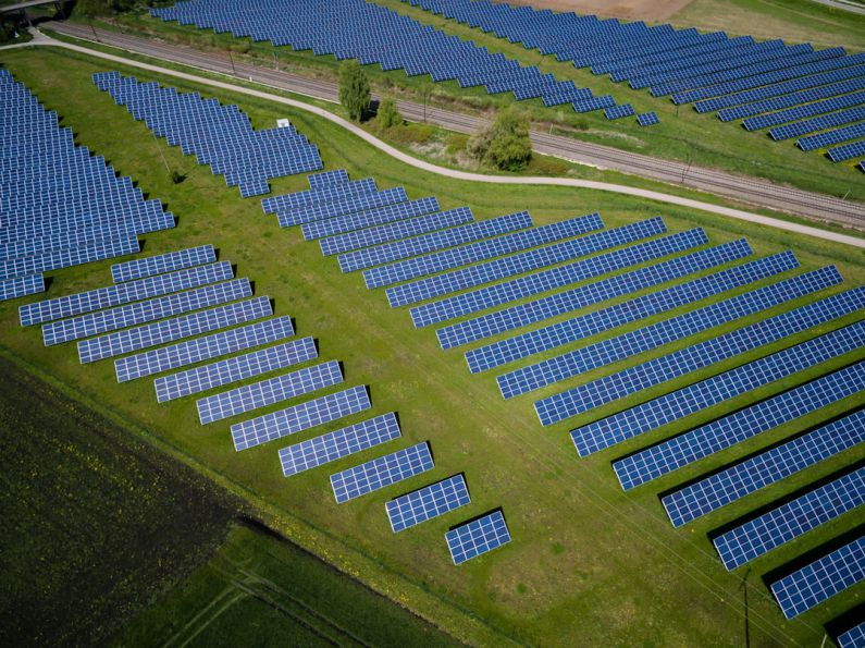 Green Energy - aerial photography of grass field with blue solar panels