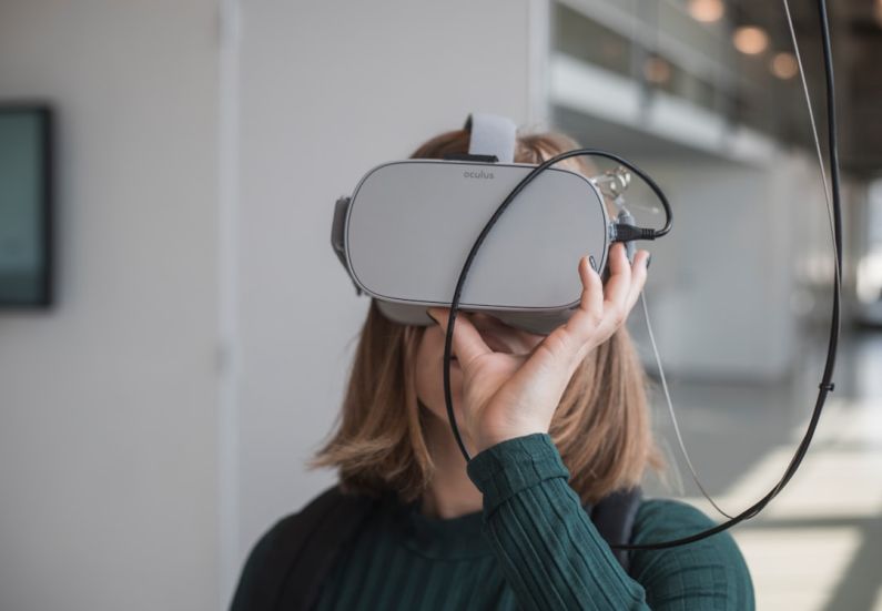 VR - woman in black sweater holding white and black vr goggles